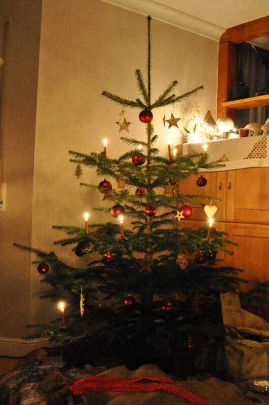 Leuchtender Weihnachtsbaum mit gelben Kerzen und roten Kugeln