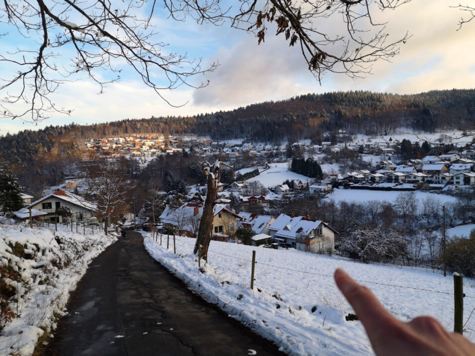 Zu sehen ist ein weiter Blick auf das Tal von Wilhelmsfeld, Ich weise mit dem Finger auf ein Haus am Hang