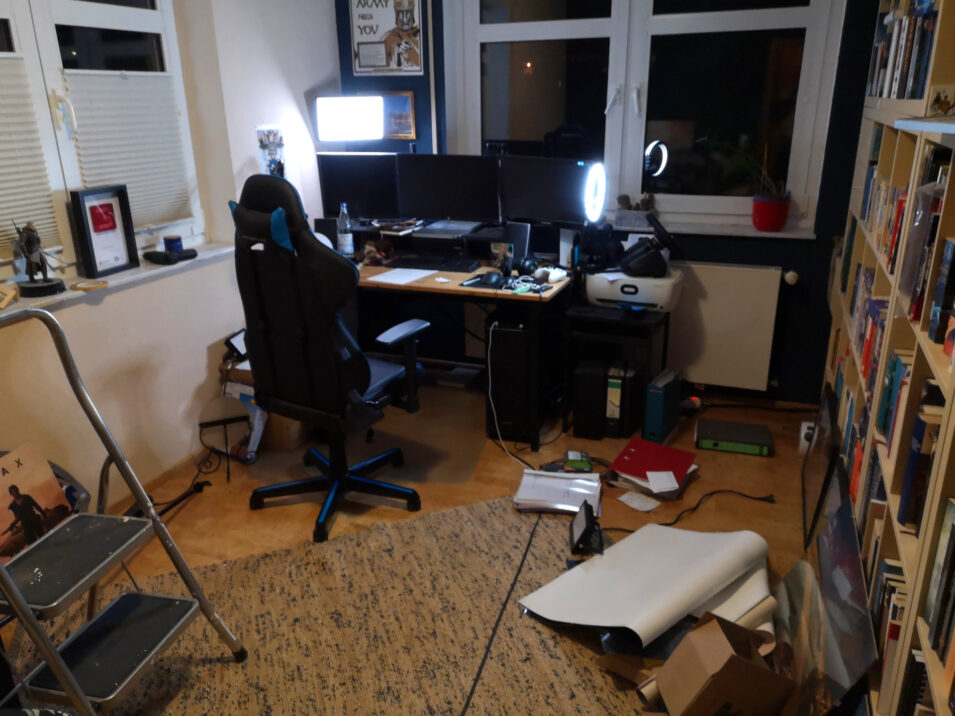 Mein Arbeitszimmer mit Schreibtisch und Computer, dazwischen eine kleine Leiter und Zeug am Boden
