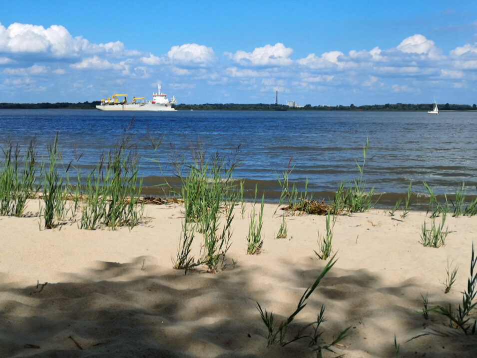 Foto vom Sandstrand an der Elbe mit Schiff auf dem Wasser