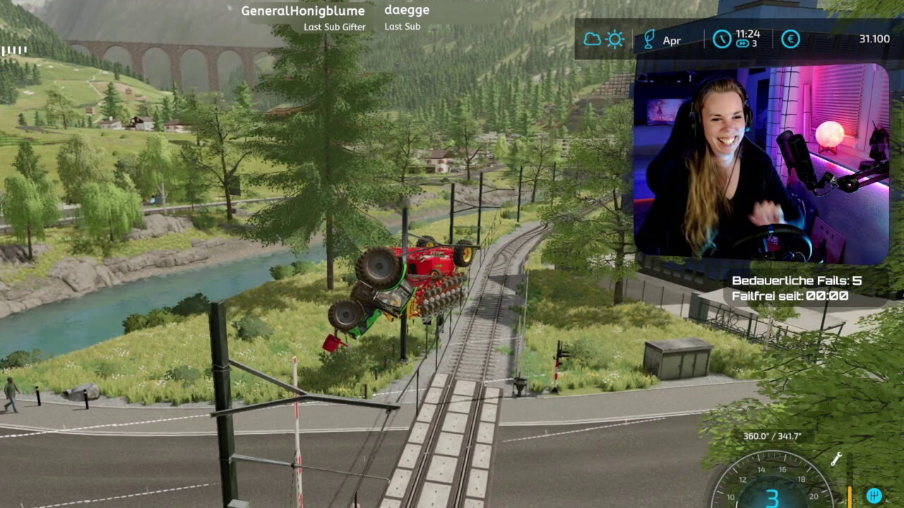 Screenshot aus einem Stream: Rechts oben im Webcambild ist Lucyda, sie lacht. Das Gameplay zeigt einen Ausschnitt aus Landwirtschafts-Simulator 2022. Mein Traktor wurde vom Zug überrollt und auf eine Stromleitung geschleudert, wo er nun herumbaumelt. Das Bild zeigt eine der richtig schönen Situationen aus meiner Streamingzeit.