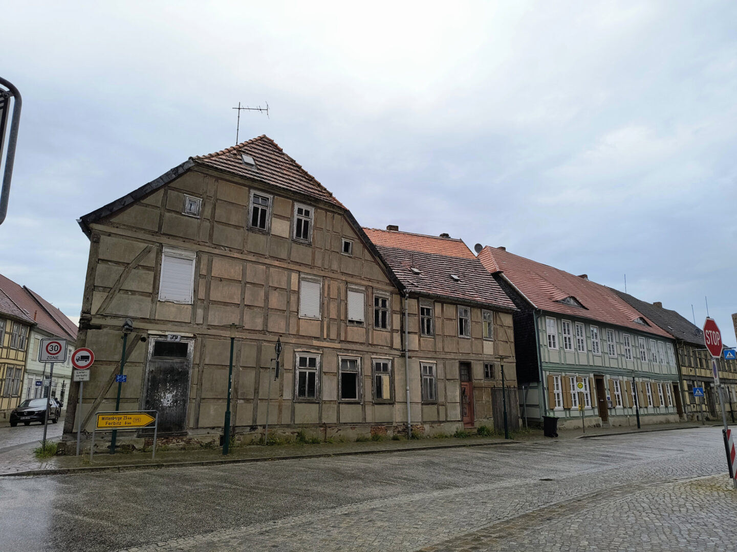 Alte Fachwerkhäuser, die an einem kopfsteingepflasterten Bürgersteig stehen. Die Straße ist leer. Einige Häuser stehen ebenfalls sichtlich leer, die Rolladen sind heruntergelassen.